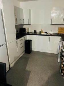 a white kitchen with white cabinets and a sink at One Bedroom Apartment Barking in Barking