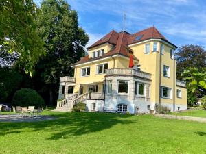 uma grande casa amarela com um telhado castanho em Villa Schwanenblick - eine besonderes Feriendomizil mit direktem Seezugang und Slipanlage em Nonnenhorn