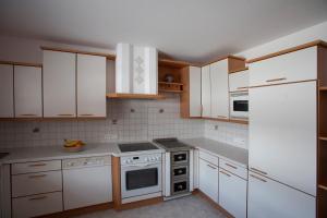 una cocina con armarios blancos y electrodomésticos blancos en Appartement STAUDEN, en Innervillgraten