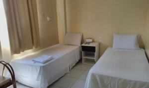 a small room with two beds and a night stand at Barrudada Palace Hotel-Boa Vista in Boa Vista