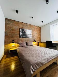 a bedroom with a large bed and a brick wall at Brick Apart Melnyka10 in Ivano-Frankivsʼk