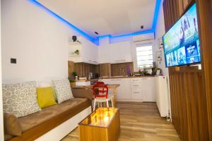 een woonkamer met een bank en een keuken met een tv bij Thessaloniki Amazing Apartment in Thessaloniki