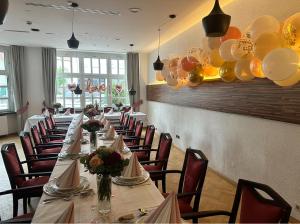 a long table in a room with chairs and balloons at Hotel Schuetzenhaus Vorsfelde in Wolfsburg