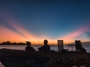 two people sitting in a boat watching the sunset at Beach Cottage in Rasdhoo