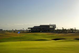 um campo de golfe verde com um edifício ao fundo em Prestigia appt rez de jardin golf em Marrakech