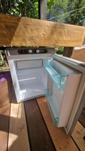 an empty refrigerator with its door open under a bench at Glamping Štôla- Symbioza in Štôla