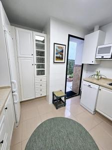 una cucina con armadi bianchi e un tappeto verde di Apartamento Vetalegua Jerez a Jerez de la Frontera