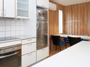 una cocina con armarios blancos y una mesa con sillas. en Holiday home Egå III en Egå