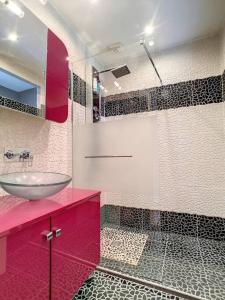 La salle de bains est pourvue d'un lavabo et d'un comptoir rouge. dans l'établissement Oasis urbaine à LYON - jardin& jacuzzi, à Lyon