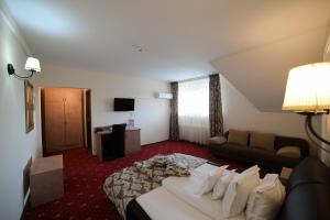 um quarto de hotel com uma cama e um sofá em Hotel-Restaurant Oscar em Piatra Neamţ