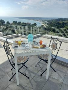 a white table and chairs with food on a balcony at Villa Caravaggio Comfort e Relax in Rocca San Giovanni