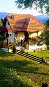 ein Haus mit einem orangenen Dach und einem Zaun in der Unterkunft Kuca za odmor Drina & Tara in Bajina Bašta