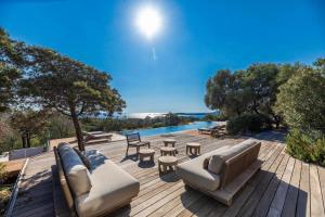 un patio con divano, tavoli e piscina di Villa Sud Corse 6ch piscine 27m, accès mer a Pianottoli-Caldarello
