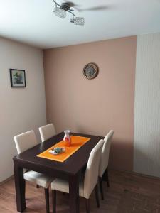 einen Esstisch mit weißen Stühlen und eine Uhr an der Wand in der Unterkunft Kuca za odmor Drina & Tara in Bajina Bašta