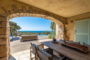 un arco in un patio con un tavolo e un divano di Villa Sud Corse 6ch piscine 27m, accès mer a Pianottoli-Caldarello