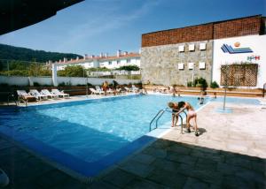 a couple of people standing in a swimming pool at Apartamentos Sarga Sentirgalicia in Cabañas