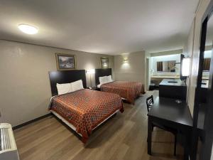 a hotel room with two beds and a desk at Royal Inn Motel in Fredericksburg