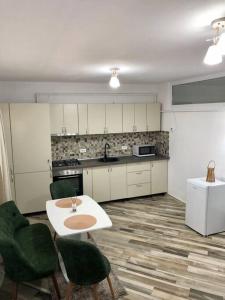 a kitchen with a white table and green chairs at Garsonieră- Bulevard Dem Rădulescu in Râmnicu Vâlcea