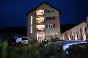 un bâtiment avec des voitures garées devant lui la nuit dans l'établissement Hotel-Restaurant Oscar, à Piatra Neamţ