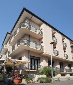 an apartment building with balconies and an umbrella at Hotel Piccinelli in Rimini