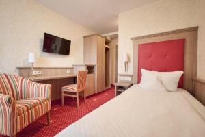 a hotel room with a bed and a chair at Hotel Wittelsbacher Höh in Würzburg