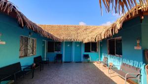 a blue building with chairs and a straw roof at Hotel & Apartments "CHEZ HIVA" in Hanga Roa