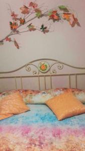 1 cama con 2 almohadas y flores en la pared en SCHITO 114 Apartments en Treia