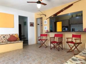 a living room with red chairs and a kitchen at Excelente casa Búzios/Geribá in Búzios
