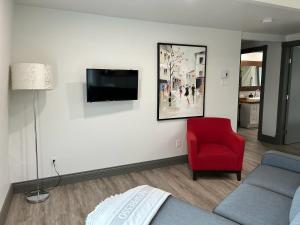 a living room with a couch and a tv on a wall at Petite Plaisance Appartements in La Malbaie