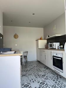 a kitchen with white cabinets and a tile floor at Appartement proche CHU in Saint-Priest-en-Jarez