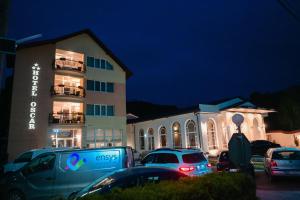un bâtiment avec des voitures garées dans un parking la nuit dans l'établissement Hotel-Restaurant Oscar, à Piatra Neamţ