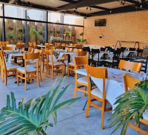 a restaurant with tables and chairs in a room with windows at Pinda Palace Hotel in Pindamonhangaba