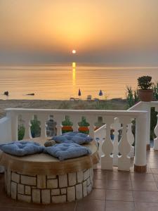 a sunset over the ocean with a bed on a balcony at Nisaki Mathraki B&B in Corfu Town