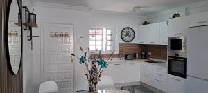 una cocina con armarios blancos y un reloj en la pared en Casa jablillo 2 en Costa Teguise