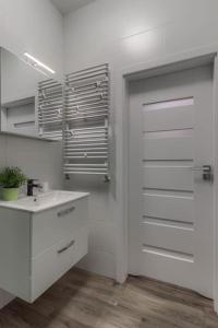 ein weißes Badezimmer mit einem Waschbecken und einer Tür in der Unterkunft Geodezyjna'70 Cozy Rooms P1 in Warschau