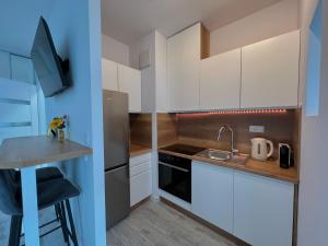 a small kitchen with white cabinets and a sink at Studio Apartment Honey by Galeria Północna in Warsaw