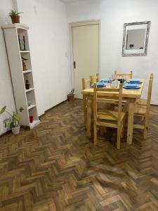 Depto La Boca في بوينس آيرس: غرفة طعام مع طاولة وأرضيات خشبية
