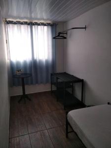 um quarto com uma cama, uma mesa e uma janela em Casa 346 em Ponta Grossa