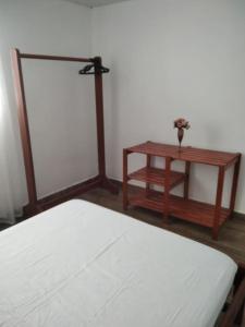 um quarto com uma cama e uma mesa com uma flor em Casa 346 em Ponta Grossa