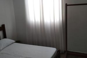 a bedroom with a white bed and a window at Casa 346 in Ponta Grossa