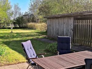 duas cadeiras e uma mesa de madeira num quintal em Holiday home Holeby em Holeby
