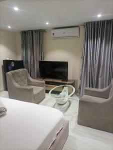 um quarto com uma cama e duas cadeiras e uma televisão em THE HAVEN SUITE em Lagos