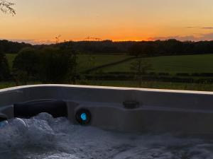 eine Badewanne voller Schnee mit Sonnenuntergang im Hintergrund in der Unterkunft The Georgian Coach House:New Forest with hot tub in Fordingbridge