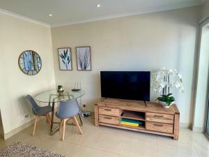 a living room with a television and a glass table at Ideal location, Mouille Point in Cape Town +2 photos