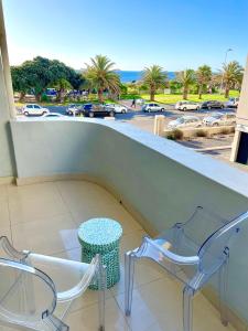a balcony with two chairs and a table and a view of a parking lot at Ideal location, Mouille Point in Cape Town