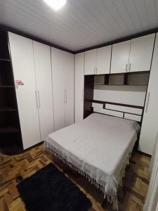 una camera da letto con un letto con armadi bianchi e un tappeto di Casa com piscina em Torres/RS a Torres