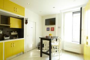 cocina con mesa negra y armarios amarillos en Affittacamere Arosio, en Monza