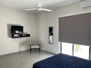a bedroom with a bed and a tv and a chair at Excelente Departamento en planta baja colonia Altabrisa in Mérida