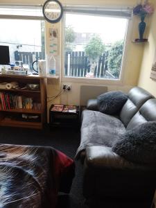a living room with a leather couch and a window at STUDIO PAD in Cardiff