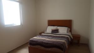 a small bedroom with a bed and a window at ORQUIDEA in Irapuato